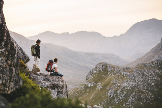 Hiking couple resting on a mountain outcrop overlooking the view of a scenic valley