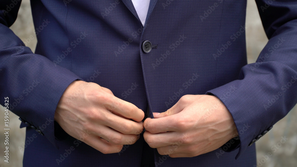 Wall mural The man fastens buttons on his jacket close up.