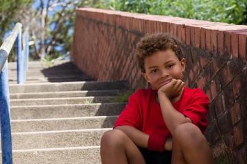 Boy sitting on staircase in the boot camp on a sunny day