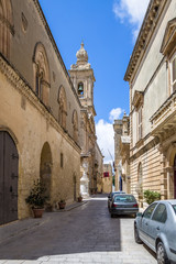 Fototapeta na wymiar Old Narrow Street of Mdina with Carmelite Church Bell Tower - Mdina, Malta