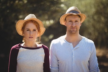 Young couple wearing hat on sunny day at farm