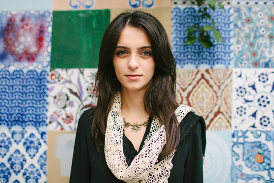 Portrait of Mediterranean woman in front of painted tiles