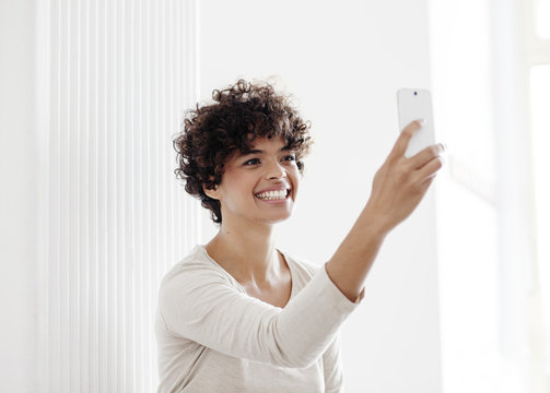 Beautiful young woman taking a selfie photo with phone