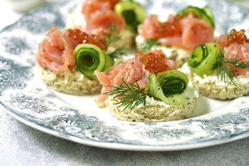 Canape with salmon,cucumber and red caviar on a curd spread.