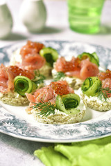 Canape with salmon,cucumber and red caviar on a curd spread.