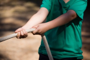 Boy practicing tug of war during obstacle course 