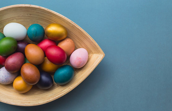 Bunch of colorful Easter eggs in wooden plate