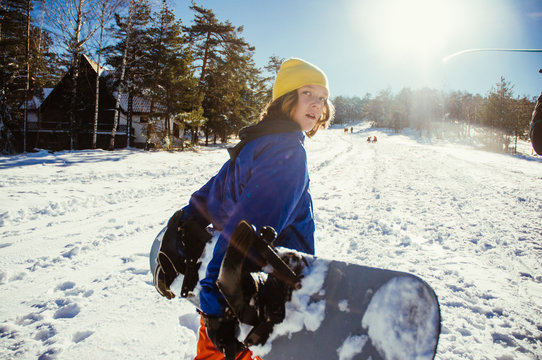 Young snowboarder holding his snowboard