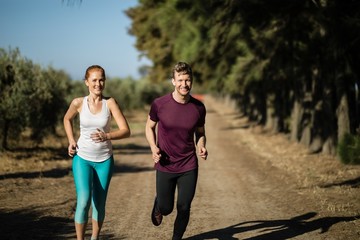 Portrait of young couple running during sunny day