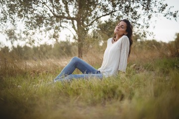 Young woman resting on grassy field at farm