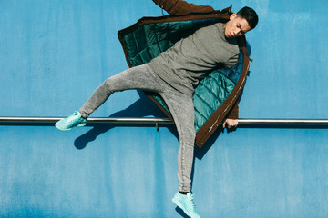 Asian modern man jumping in front of a blue wall