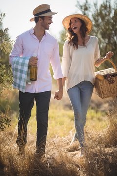 Cheerful young couple carrying picnic basket