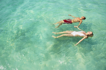 Couple holding hands floating in the ocean