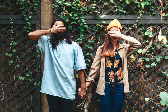 Young Hipster Couple Hiding Their Faces On Ivy Background 