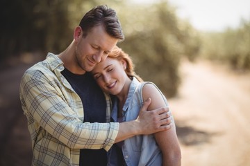Smiling couple embracing on field at olive farm - Powered by Adobe