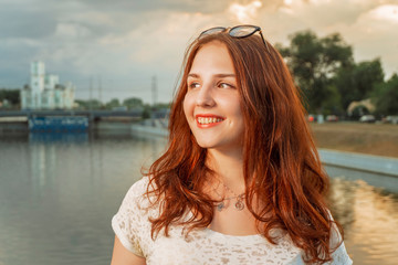 Portrait of a smiling young red haired woman over city river landscape