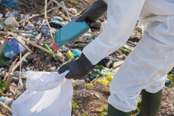 Volunteer man in white protective clothing collects garbage