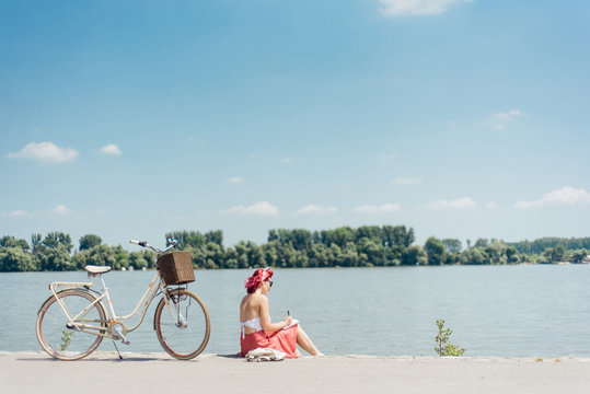 Young woman enjoying a sunny day at river bank and drawing