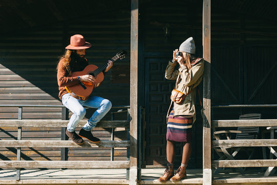 Hipster couple enjoying a sunny day on a cabin porch