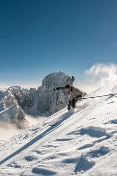 young man is skiing down a steep slope in old, nostalgic skiing equipment