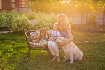 Mother and her daughter and son in the garden with a golden retriever dog