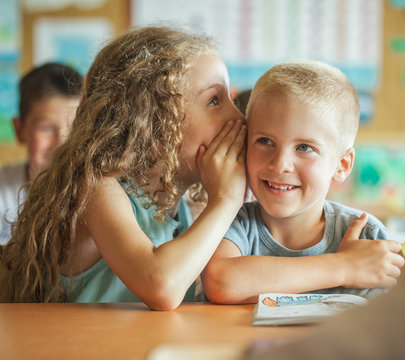 Girl Whispering Something to Her Classmate
