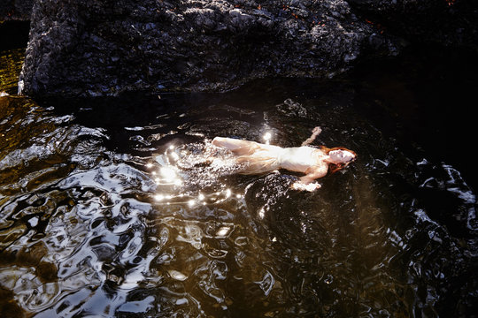 Beautiful redhead woman floating in water 