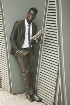African young businessman looking at camera with a newspaper