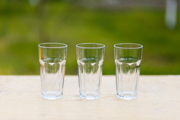 Three empty glass transparent cup on the table against the background of the chair and sofa
