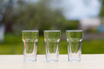 Three empty glass transparent cup on the table against the background of the chair and sofa