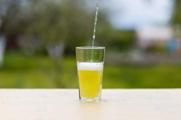 An energy drink is poured from the jar into a glass on a wooden table.