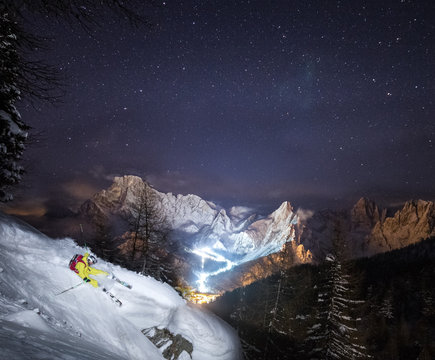 Skier riding down a powder slope at night