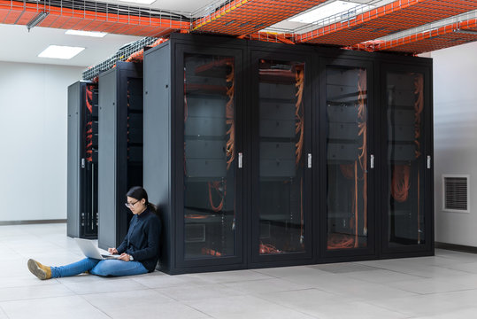 Female technician using a laptop while sitting in data center
