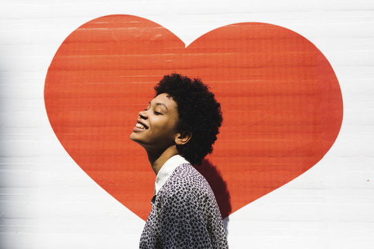Beautiful woman smiling in the sun with a heart drawn in the background