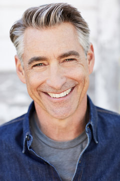 Portrait of mature man with grey hair in front of white farmhouse