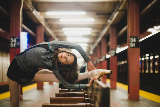 Ballet dancer stretching on bench while waiting for subway train