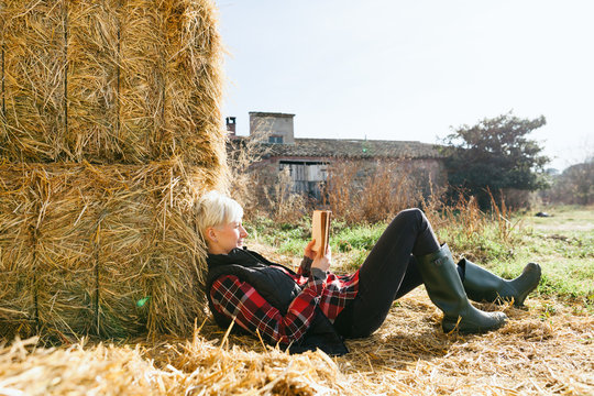Woman resting on haystack on farm
