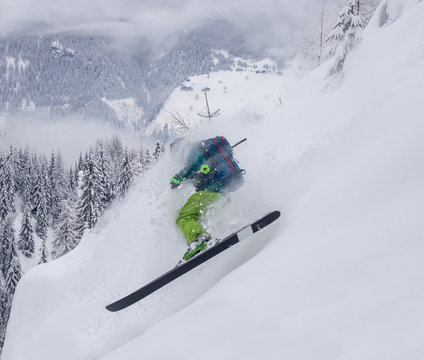 young male freerider skiing down a powder slope