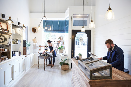Millennial owner and employee working together in artisan retail shop
