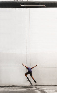 Skateboarder jumping in front of concrete wall