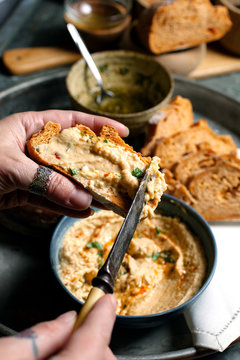 Woman's hands spreading hummus onto a slice of bread