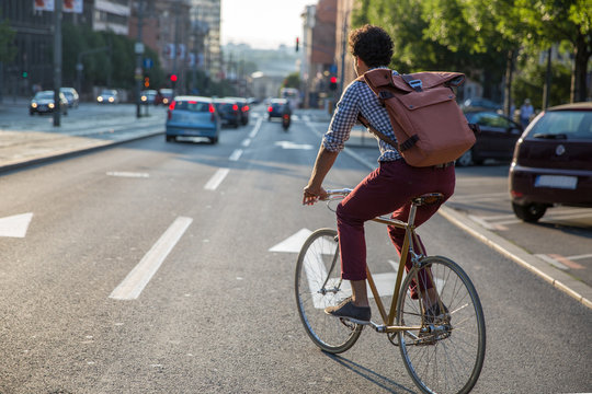 Young stylish man riding a bike to work