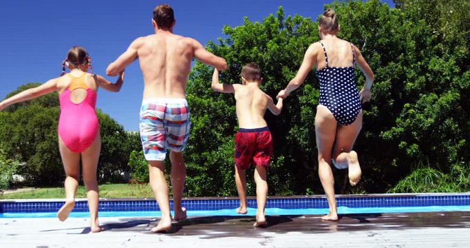 Rear view of family jumping in swimming pool