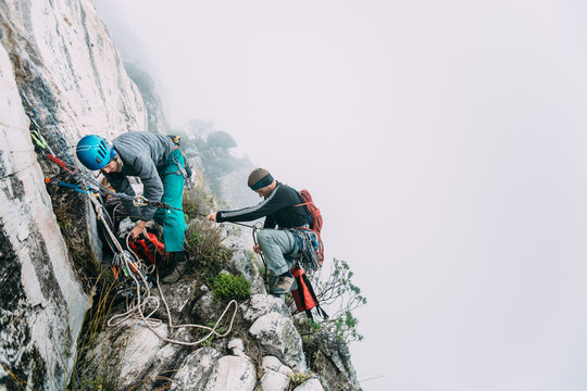 Rock climbers on a narrow ledge on a misty day in the mountains