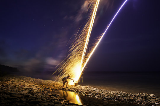 Man lighting fireworks at night