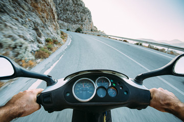 Point of view riding a moped on a winding mountain road
