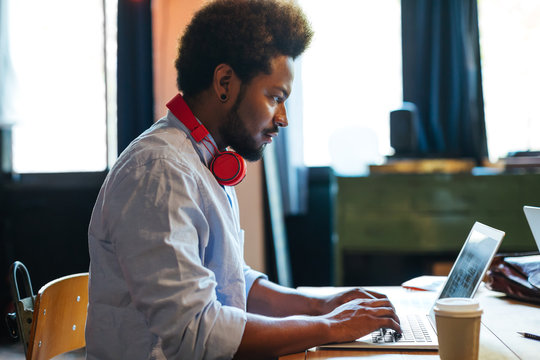 Side view of a casual businessman working on his laptop in a creative office 