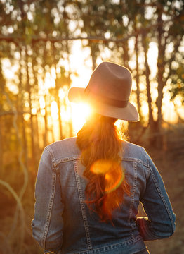 Redhead Woman In Nature Looking At Sunset Through Forest Trees