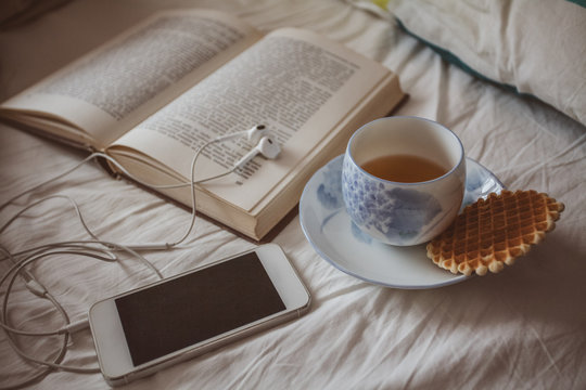 Cup of tea and open book on the bed