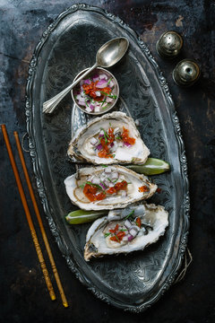 Oysters served on ornate metal platter with garnish Seen from above